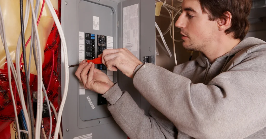 Homeowner in a basement adjusting or inspecting a residential electrical panel.