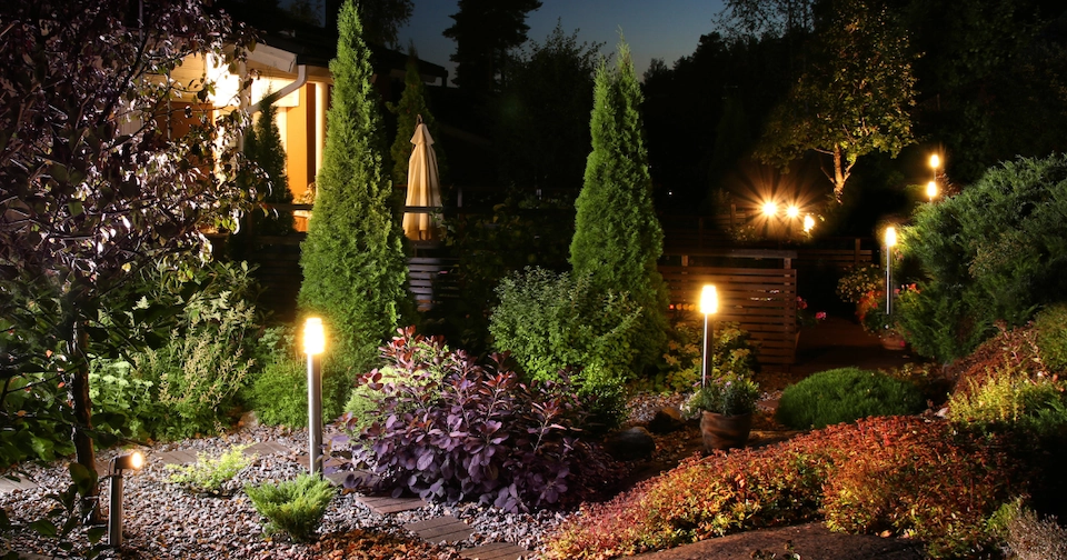 landscaped yard featuring shrubs, greenery and lighting