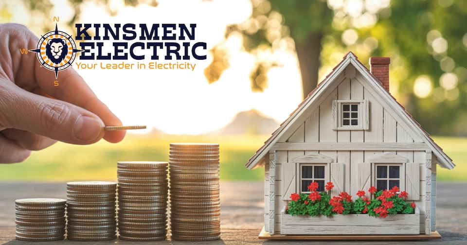 a hand stacking quarters next to a small wooden house to represent monetary and energy savings
