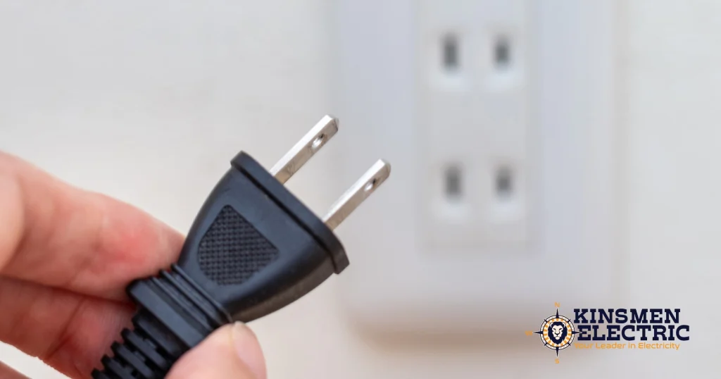 picture of a person holding a plug, about to put it into an electrical outlet inside of a home