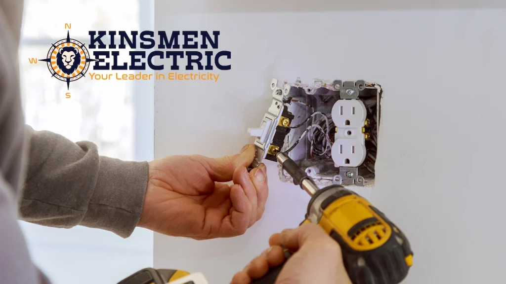 Electrician installing a wall outlet using a power drill and hand tools
