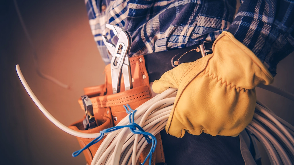 electrician holding electric cable while wearing toolbelt
