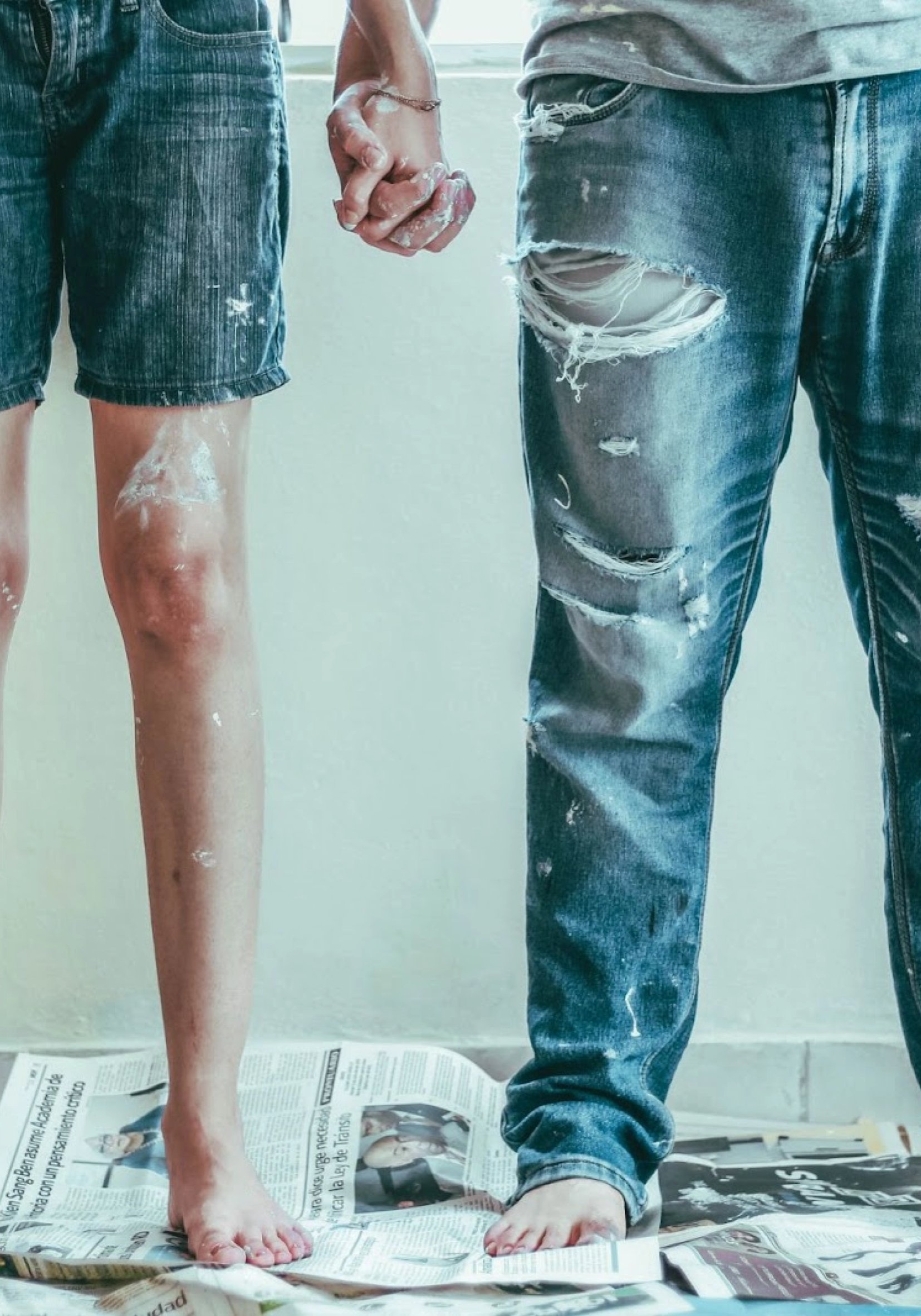 two people holding hands while painting, viewed from the waist down