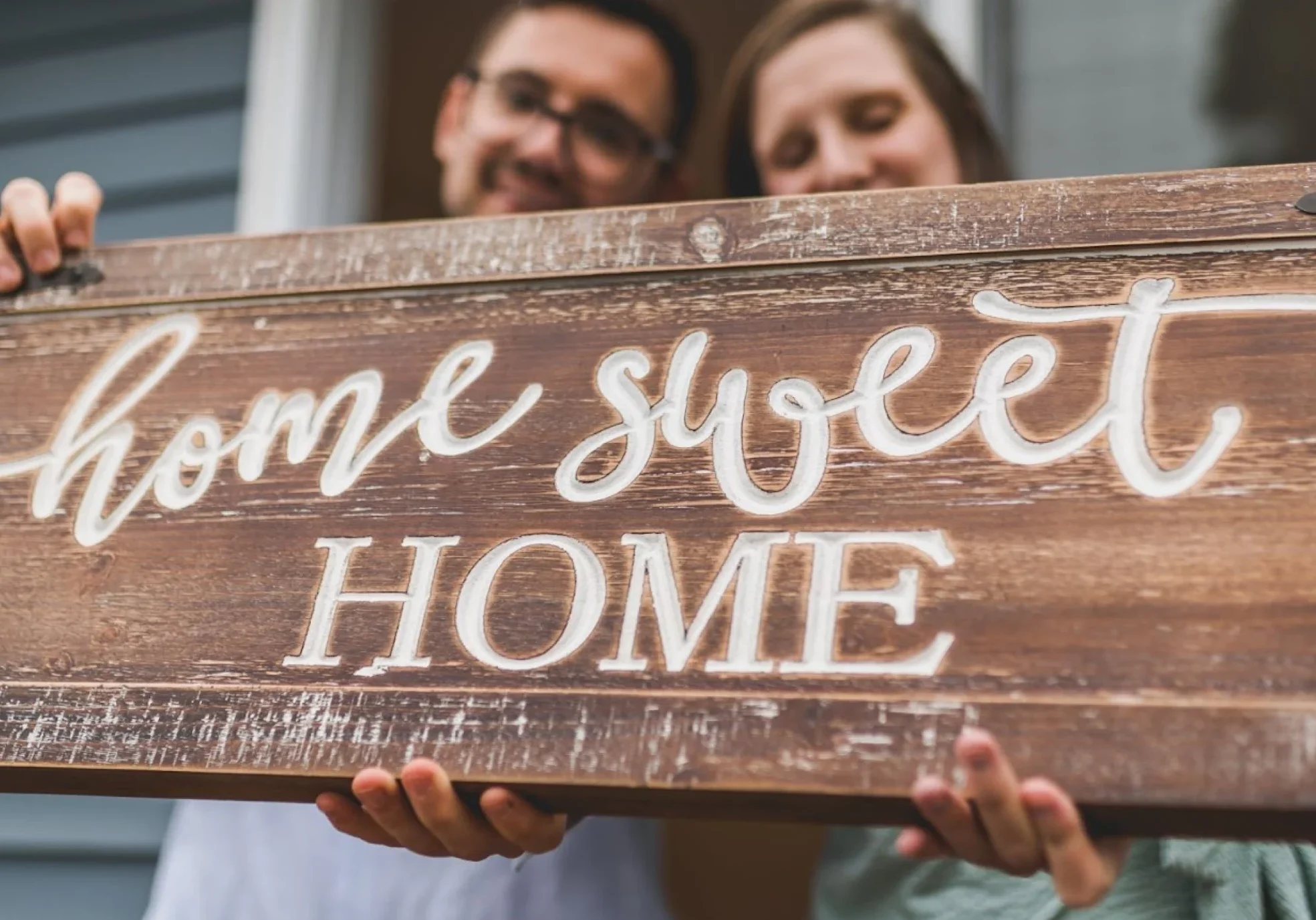 couple holding a 'home sweet home' sign